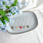 Origami butterfly earrings on a decorative plate with flowers on a light background