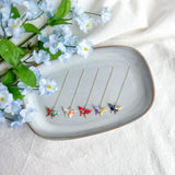 Origami butterfly earrings on a decorative plate with flowers on a light background