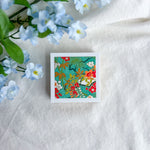 Green floral design washi paper on a white fabric background with blue flowers.