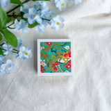 Green floral design washi paper on a white fabric background with blue flowers.