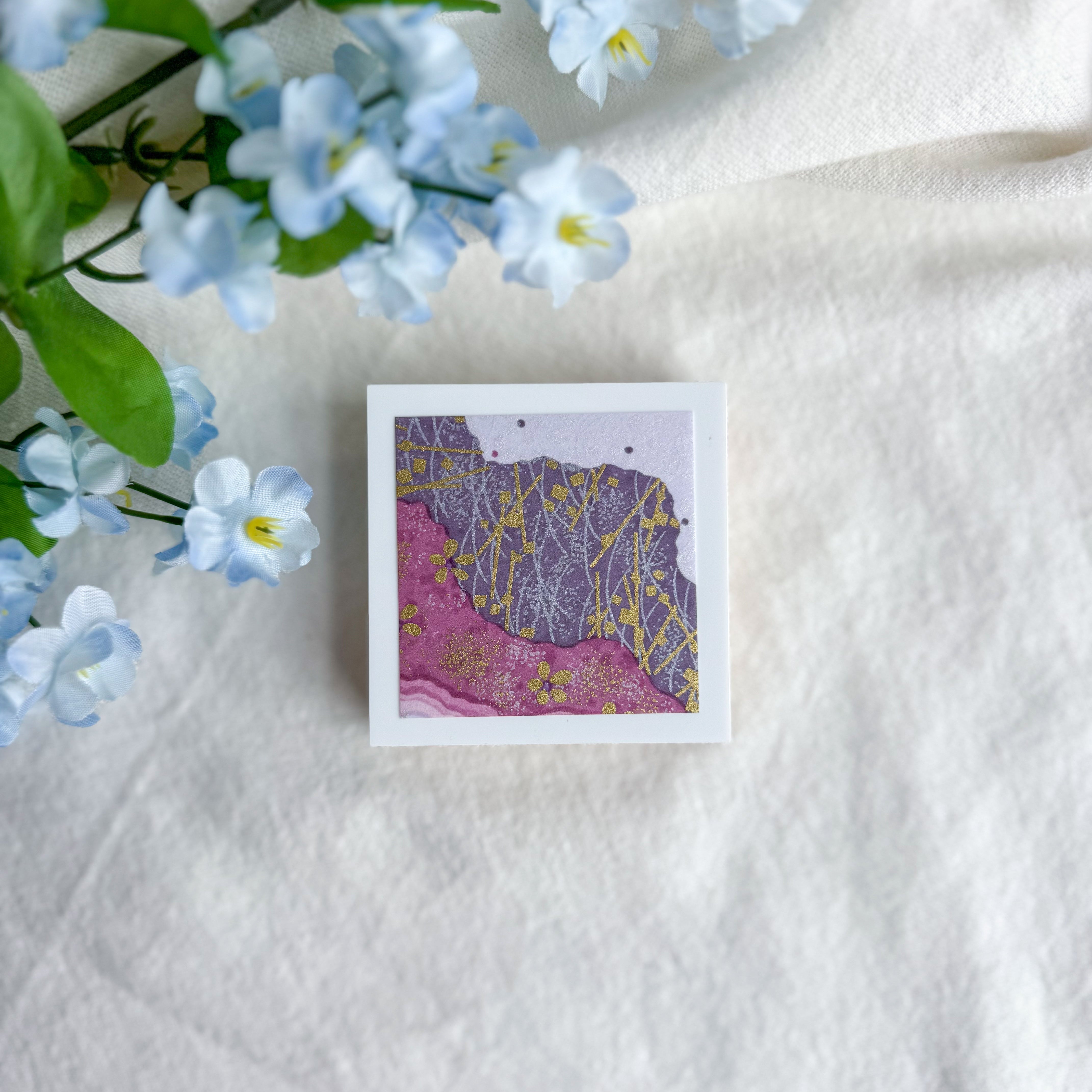 Purple floral design washi paper on a white fabric background with blue flowers.