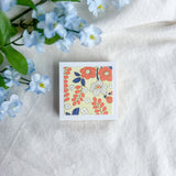 Yellow floral design washi paper on a white fabric background with blue flowers.