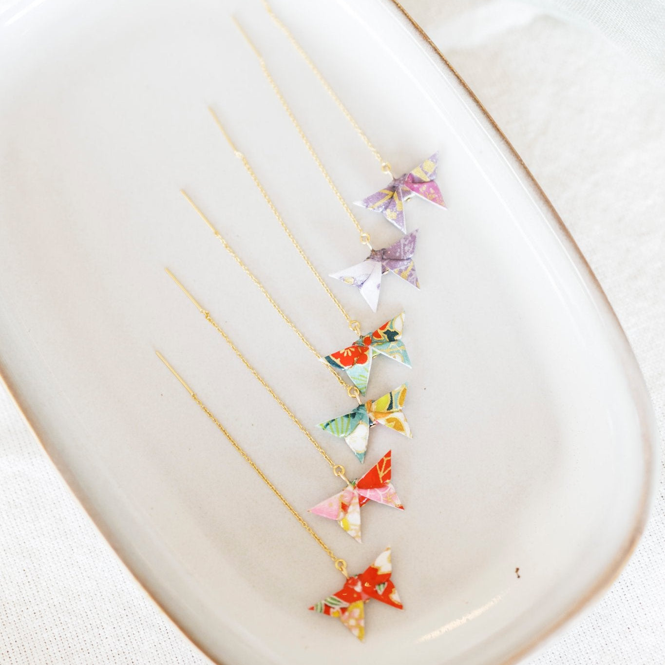 Colorful butterfly-shaped earrings on a ceramic plate