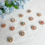 Small origami crane magnets with floral designs on a white fabric background with blue flowers.