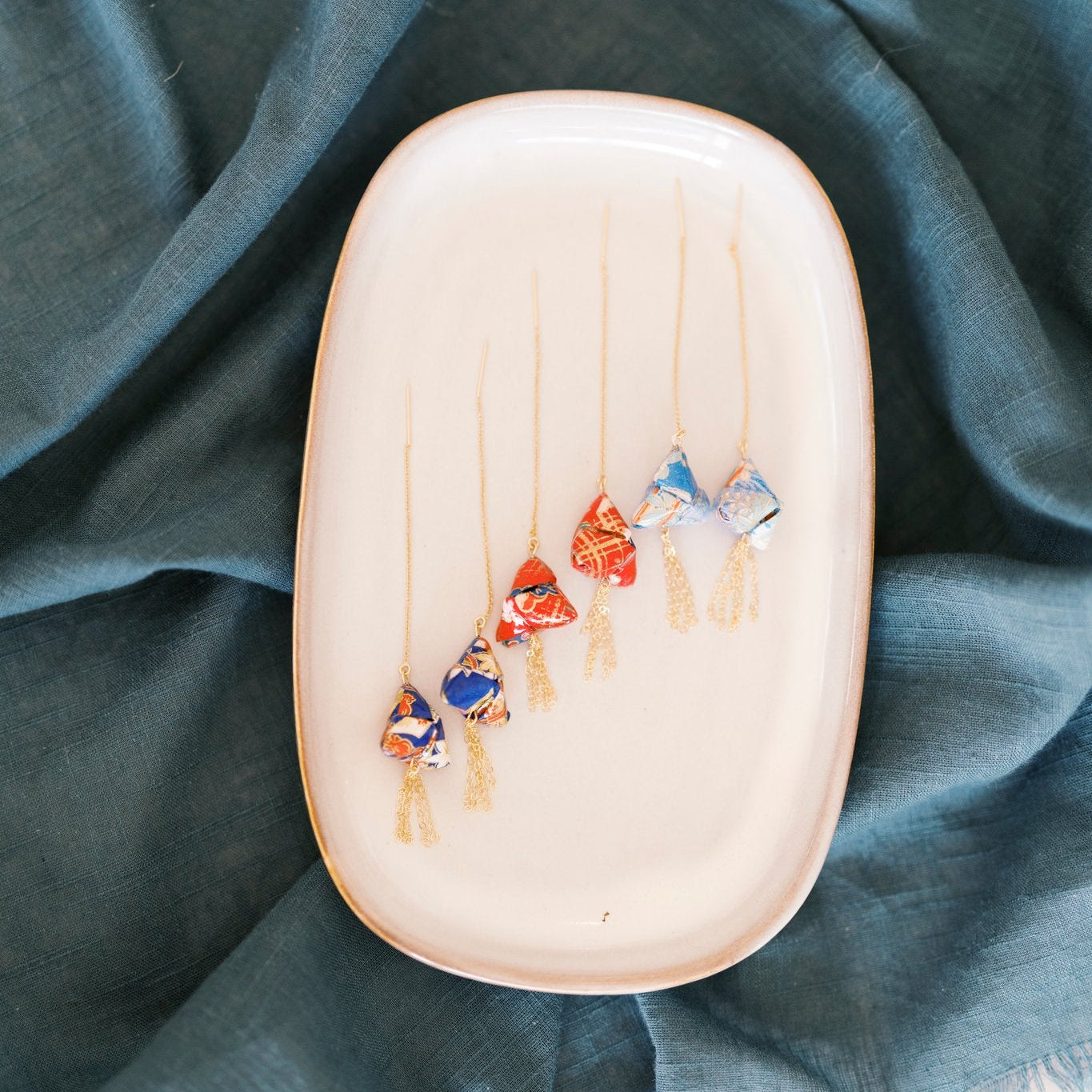 Colorful origami threaders on a plate with a teal fabric background