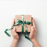 Hands holding a small gift box with a green ribbon on a white background