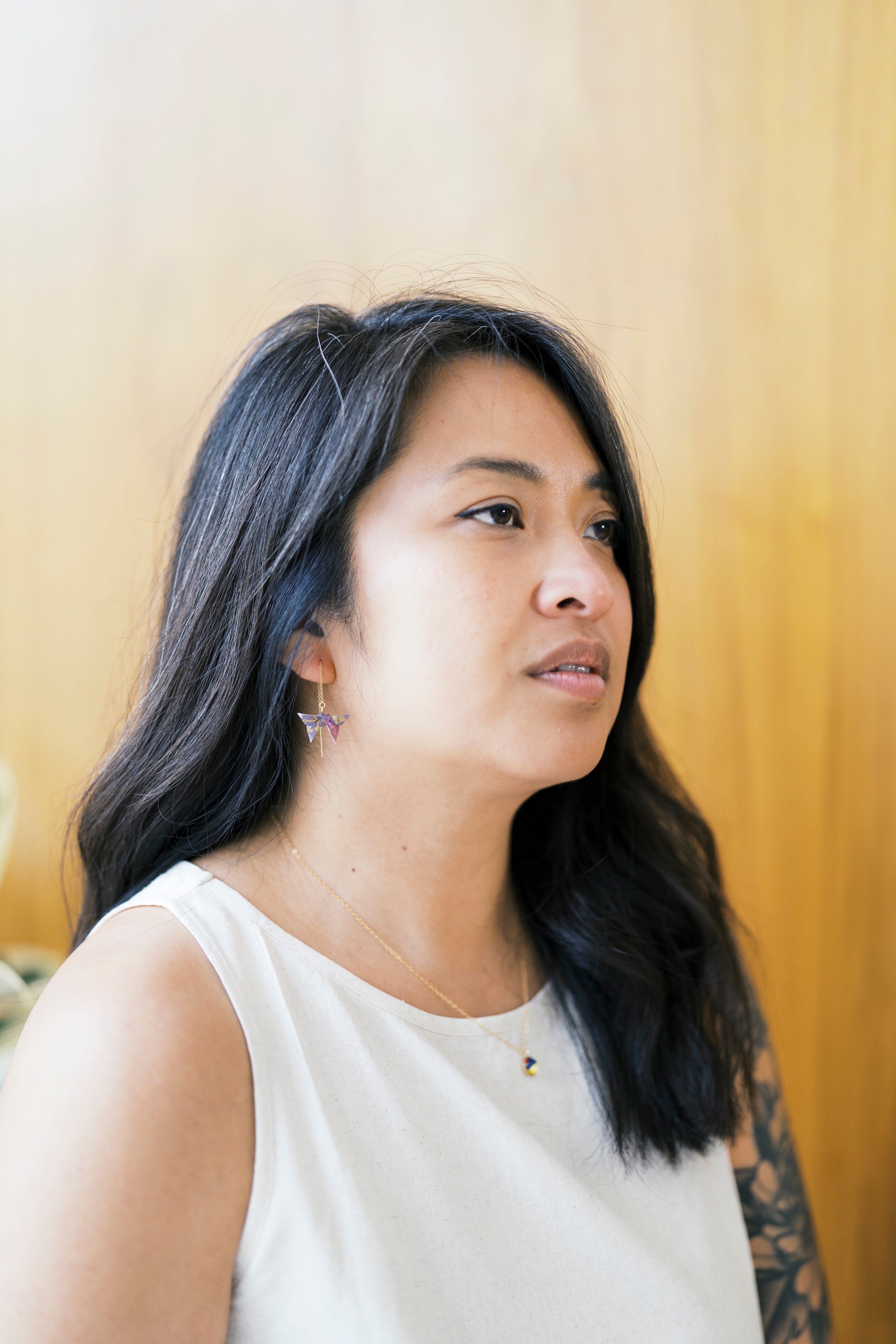 Woman with long dark hair wearing origami butterfluy thraeder earrings