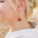 A person wearing a pair of origami crane earrings made of Japanese washi paper and 14K gold-filled findings.