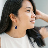 A person with dark hair wearing a pair of origami crane earrings made of Japanese washi paper and 14K gold-filled findings.