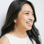 Model wearing origami leaf earrings against light background