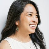 Model wearing origami leaf earrings against light background