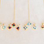 Set of origami earrings and necklaces with colorful pendants and gold disc on a light gray background
