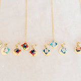 Set of origami earrings and necklaces with colorful pendants and gold disc on a light gray background