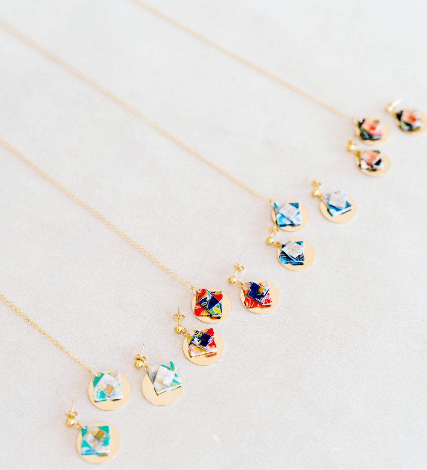 Colorful origami earring and necklace sets on grey fabric background