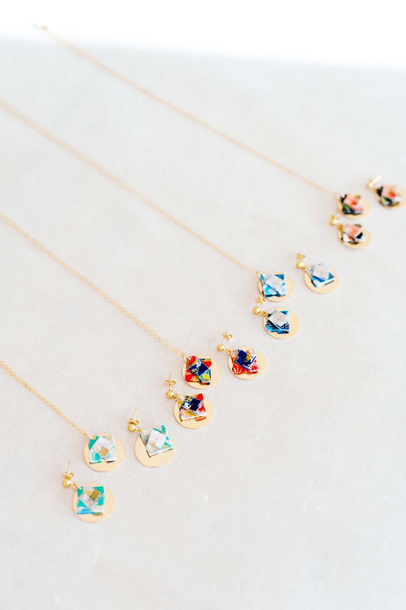 Colorful origami earring and necklace sets on grey fabric background