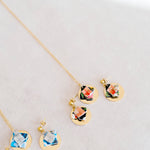 Jewelry set with floral designs and gold discon a light gray background