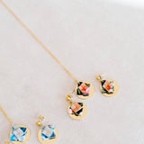 Jewelry set with floral designs and gold discon a light gray background