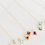 Jewelry set with floral designs and gold discon a light gray background