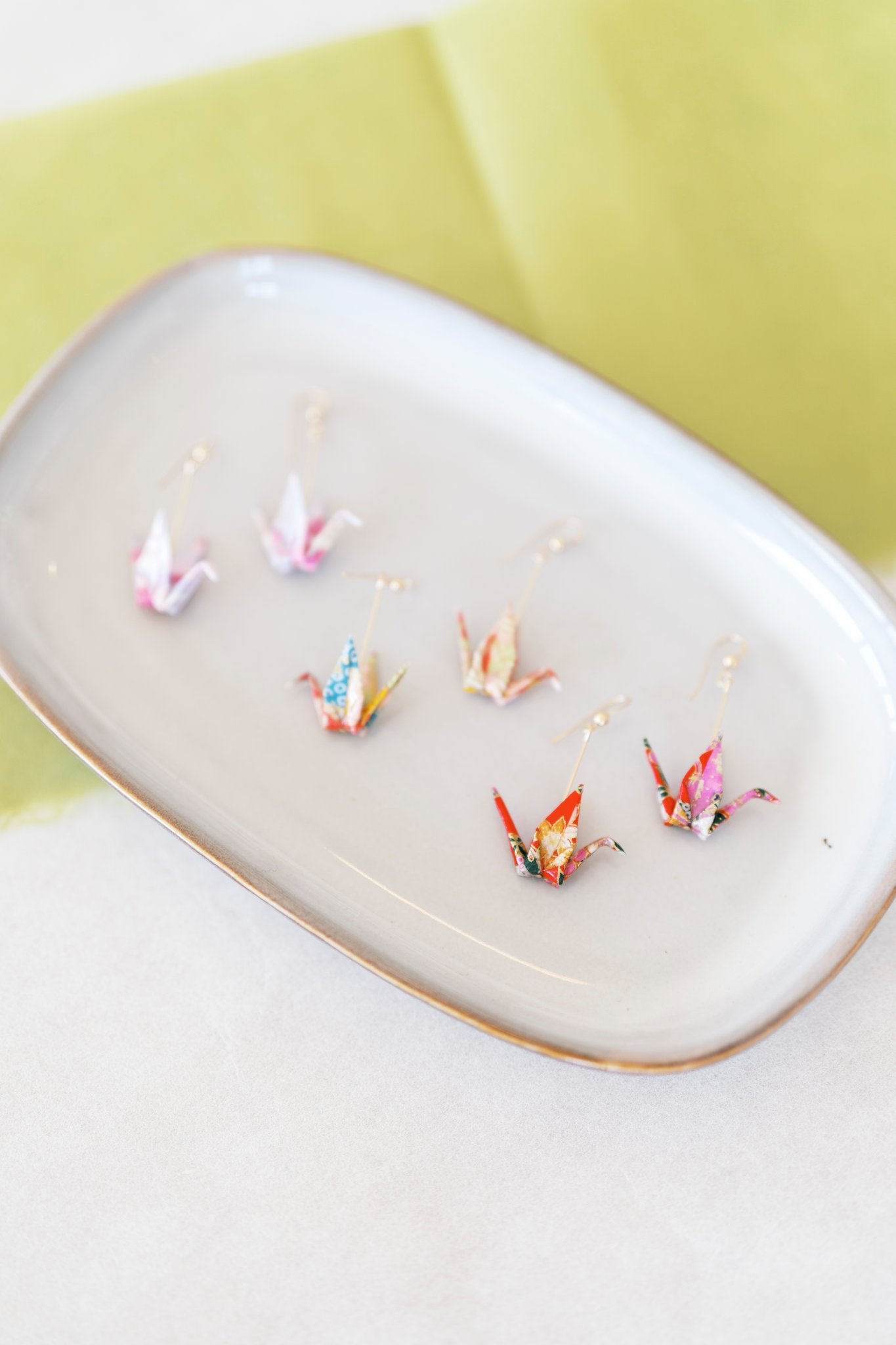 Origami crane earrings on a plate