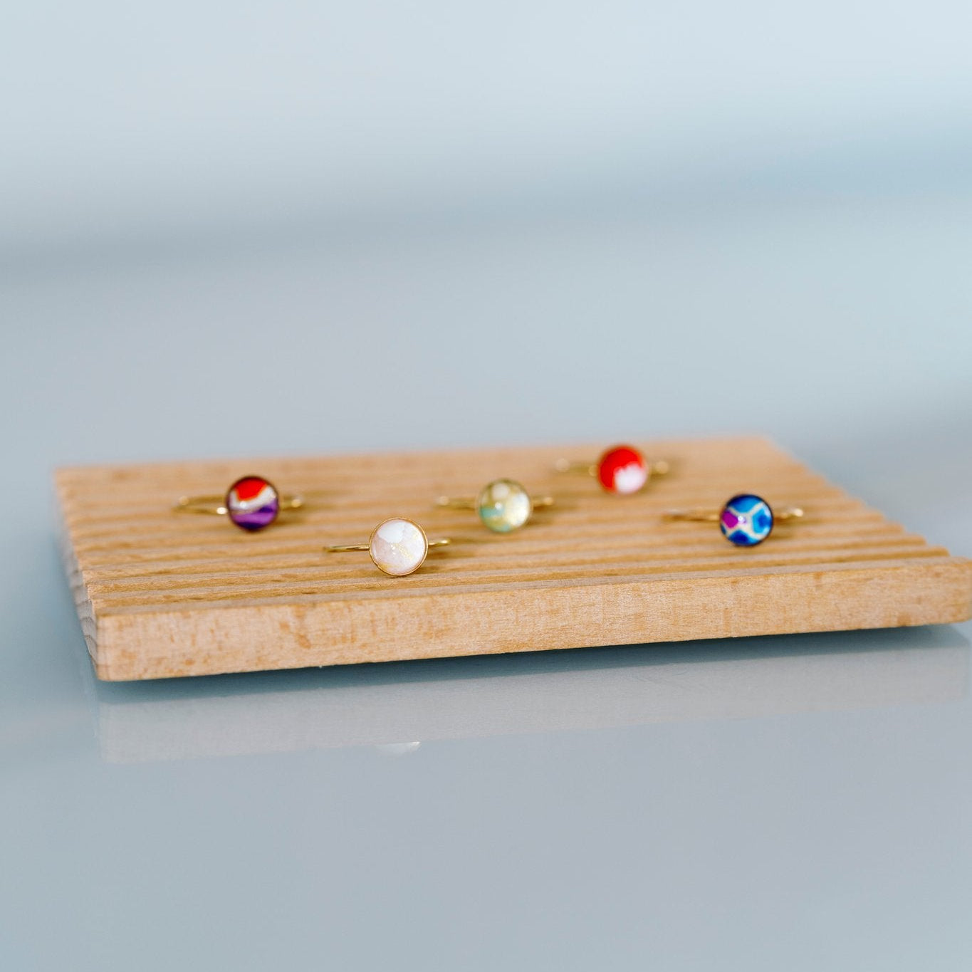 Set of colorful rings on a wooden display stand against a light background